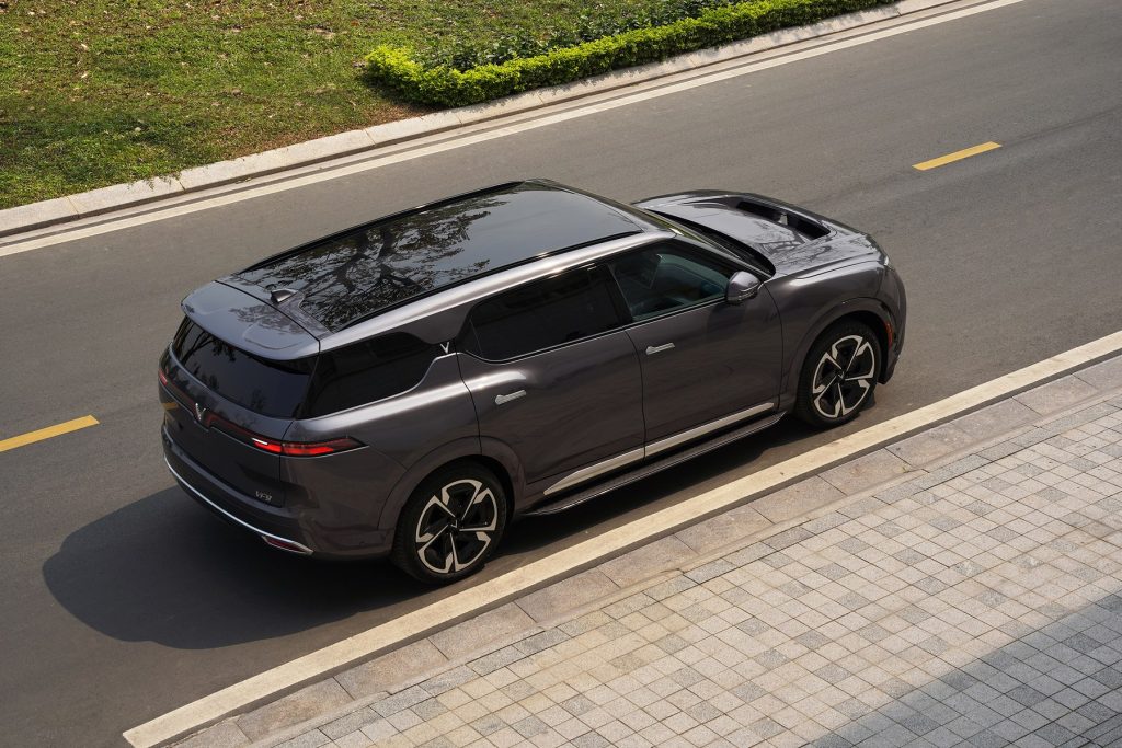 VinFast VF9 màu xám Neptune Grey nhìn từ trên cao ở góc 3/4 phía sau trên đường lát gạch